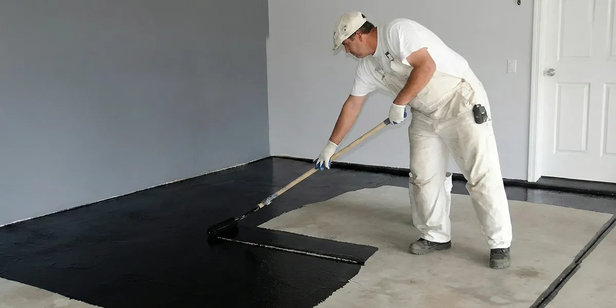basement waterproofing professional applying waterproof coating to protect a basement floor in Raleigh, NC